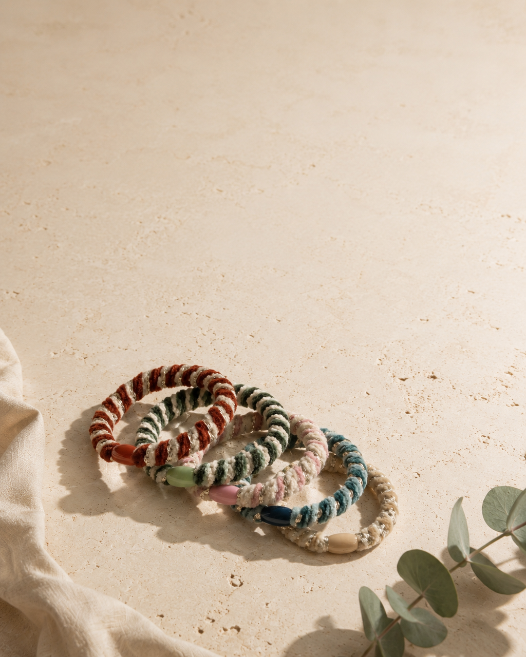 Velvet Stripe Hair Ties -hiuslenkit aseteltuna vaalealle pinnalle eukalyptuksen kanssa