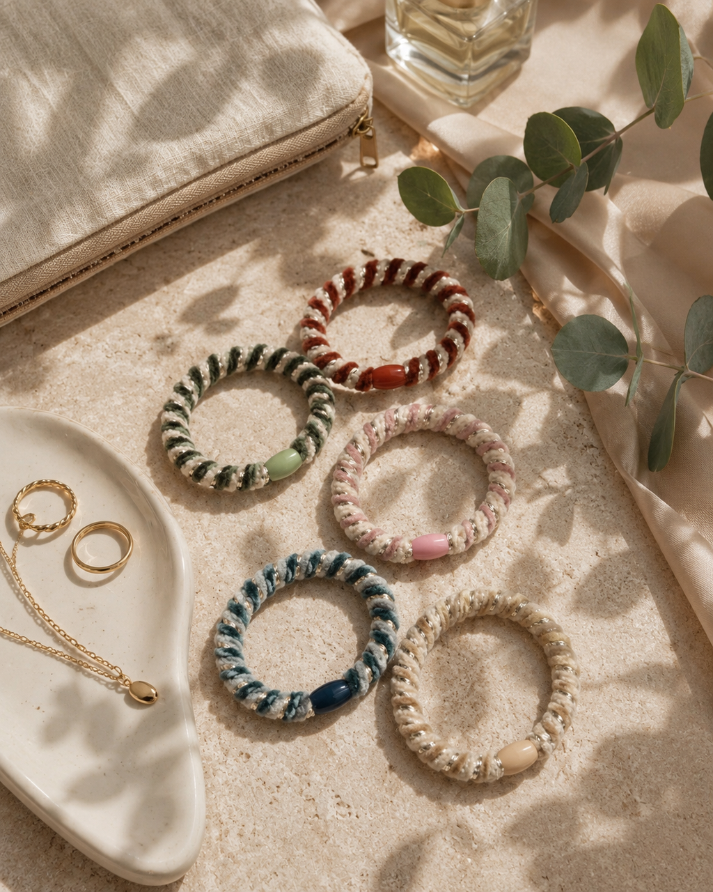 Viisi Velvet Stripe Hair Ties -hiuslenkkiä aseteltuna tasaiselle pinnalle korujen ja kasvien kanssa